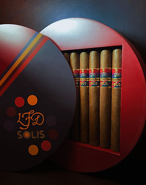 Round red La Flor Dominicana Solis gift box open to reveal cigars with Solis bands and a lid showing the LFD Solis logo.