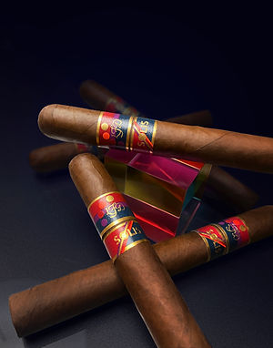 Three La Flor Dominicana Solis cigars with red and blue bands on a dark background