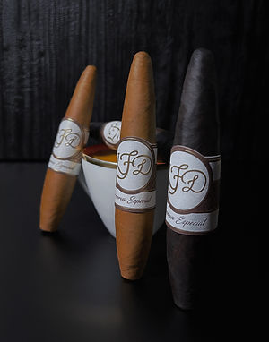 Four La Flor Dominicana Reserva Especial cigars with white-and-gold bands in a studio setting