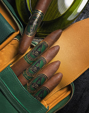 Close-up of torpedo cigars with green and gold bands showing a stylized emblem