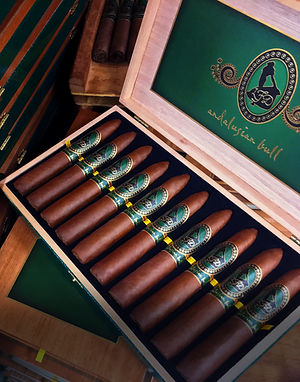Open box of La Flor Dominicana Andalusian Bull cigars with green-and-gold bands and inner lid logo