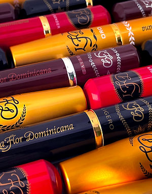 Close-up of La Flor Dominicana cigar tubes in gold, red, and black with the brand name on a tube.