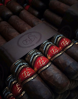 Close-up of dark cigars with red and gold bands and a branded leather sleeve