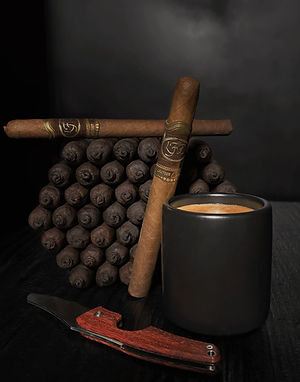 Stack of La Flor Dominicana Cameroon Cabinet cigars with gold bands next to a black cup