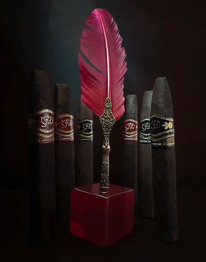 La Flor Dominicana Chapter I & Capitulo II cigars with decorative bands around a red feather pen on a dark background